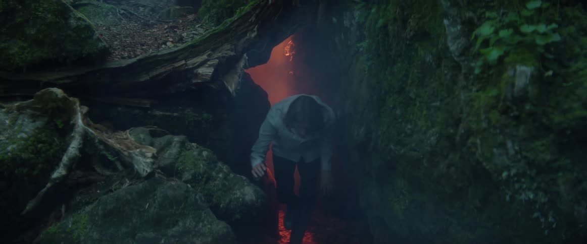 A man exits the cave in the forest