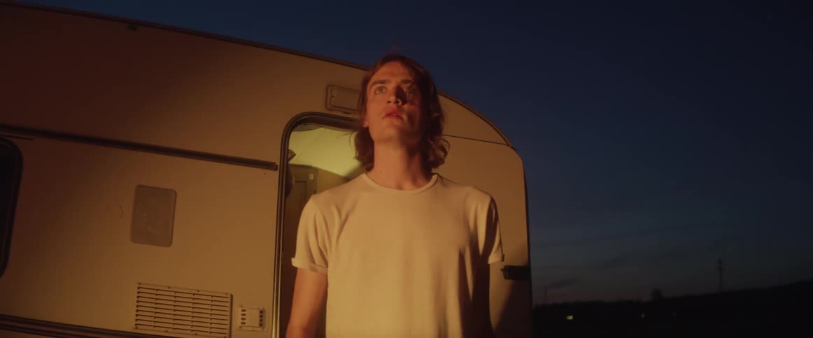 A man exiting a camper parked outside at night
