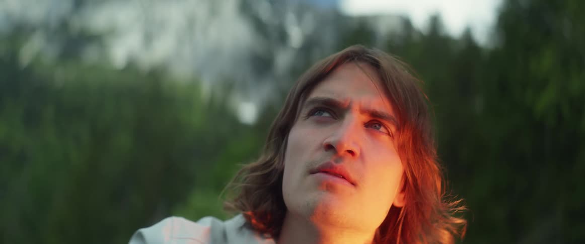 Campfire reflects on the face of the man with long hair who looks around