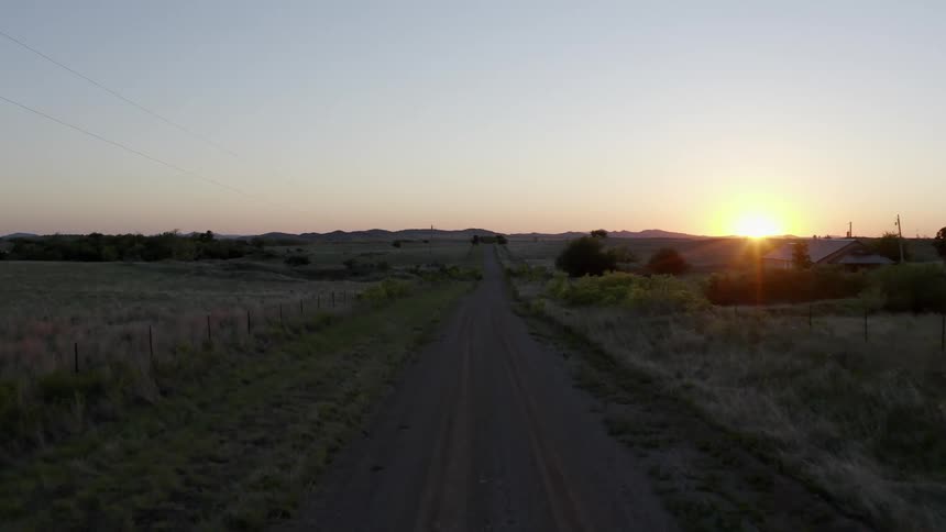 Vehicle drives on country road at sunset