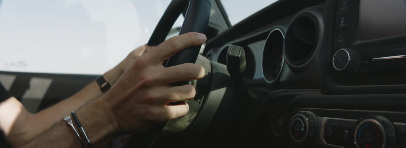 A person gripping a steering wheel while driving a vehicle