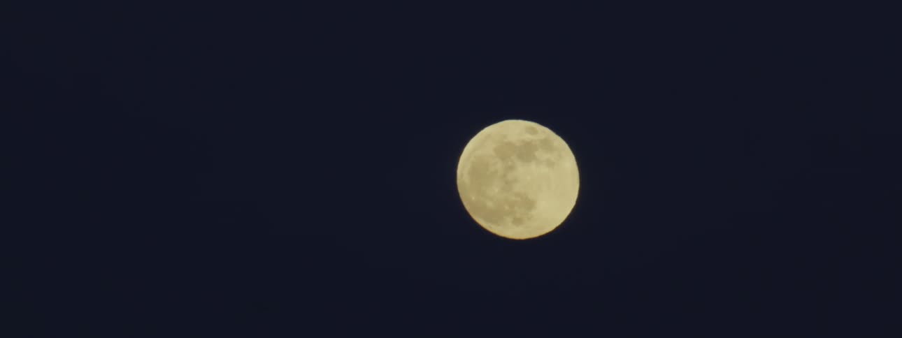 A view of a full moon as it slowly moves across the sky at night