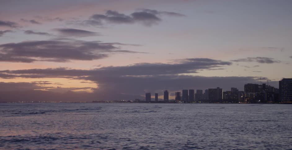 Waves roll across a bay in front of a city skyline