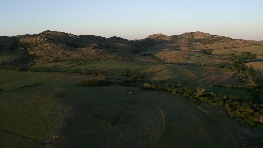The sun is setting on bare mountains and hills in the country
