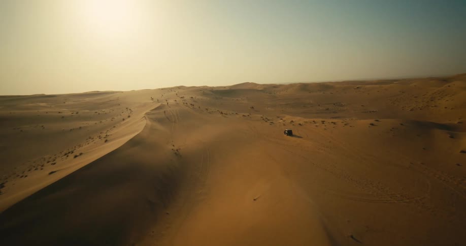 Black jeep drives across the sand dunes in the desert