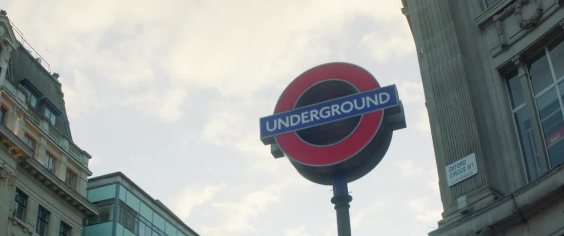 A circular sign stands among tall buildings in a city