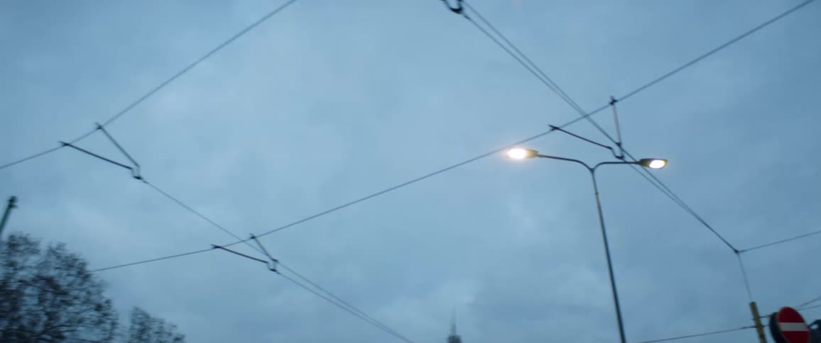 Utility pole streetlights and traffic lights with trees the sky and clouds in the background