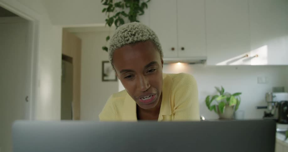 A woman is in front of a laptop looking down to her side and then talking into it