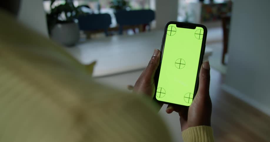 A person is standing in a room looking at a screen on a phone
