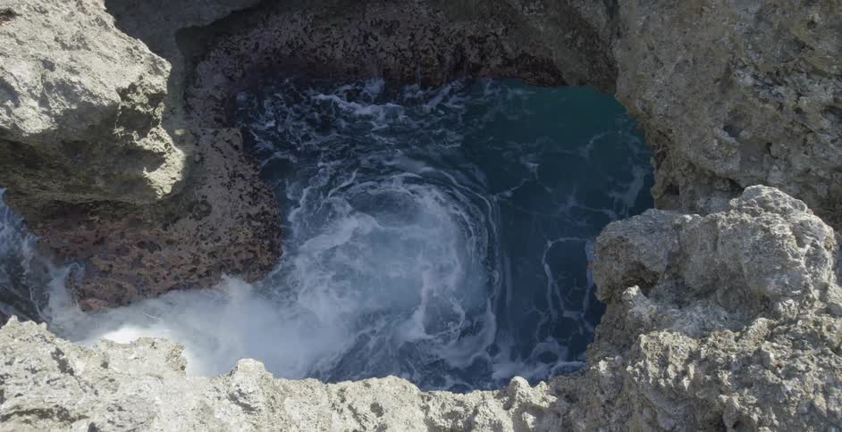 Water rashes into a spring between rocks below