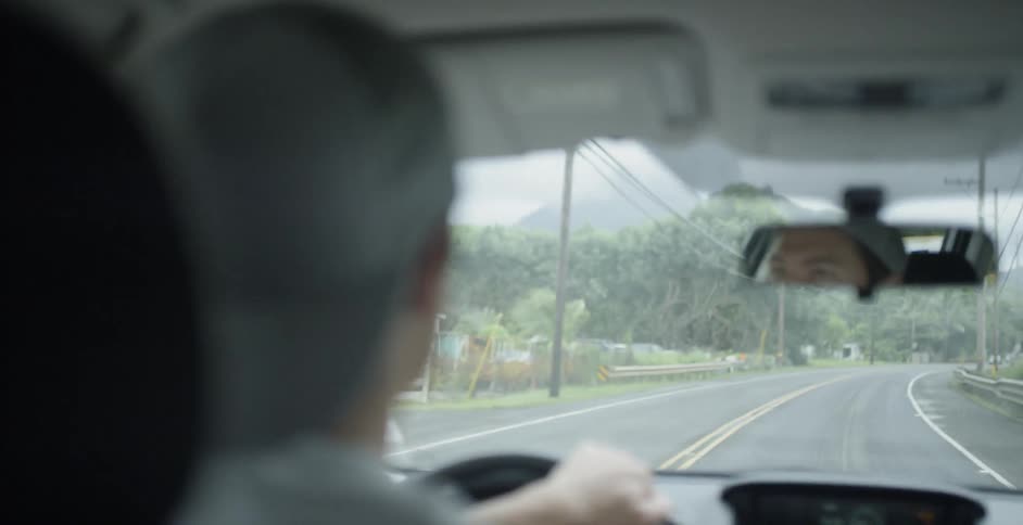 A man wearing a backwards cap drives a car