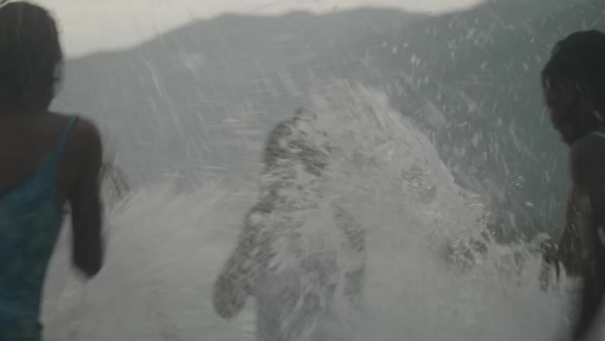 Siblings laugh as they splash each other in the ocean