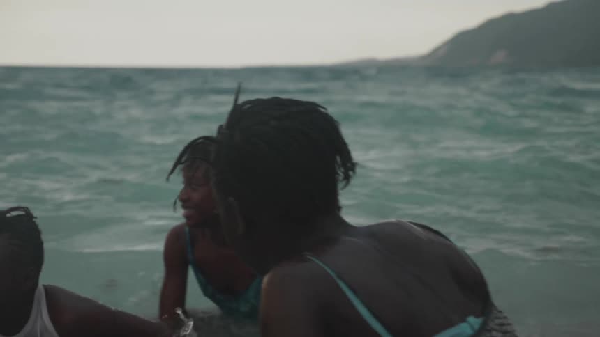 Three girls are relaxing and enjoying the tropical waters at a beach on an overcast day