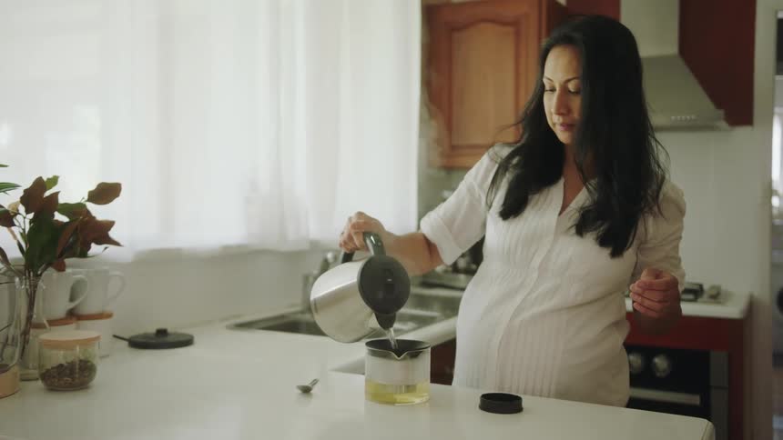 A woman pours hot water into a tea kettle