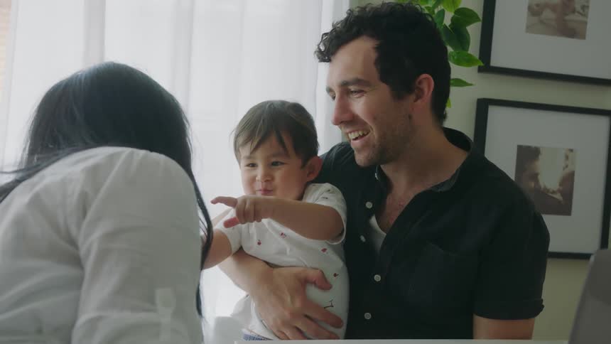 A young mother and father kiss their son