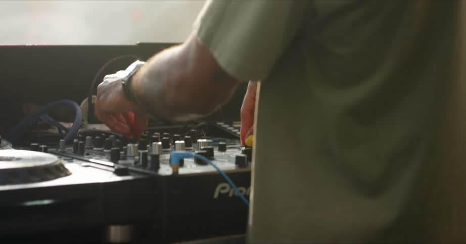 A man with a wristwatch djing turning knobs and dancing