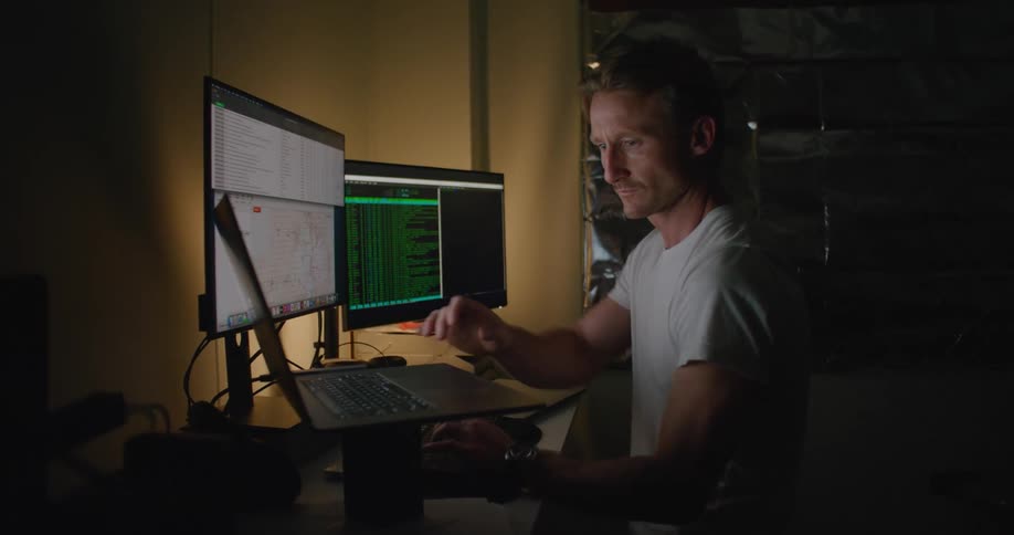 A computer programmer is working at a home workstation during the night