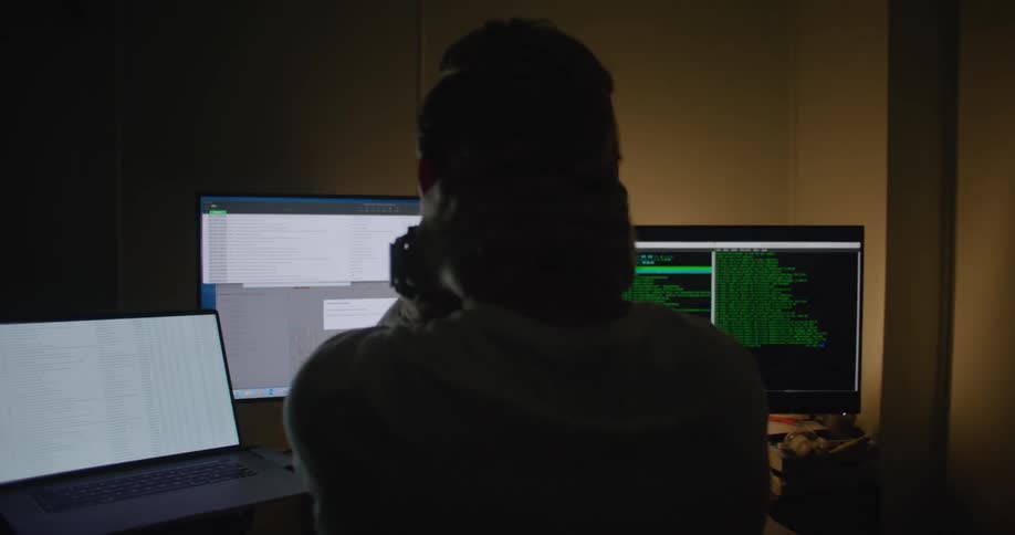 A man is looking at three monitors