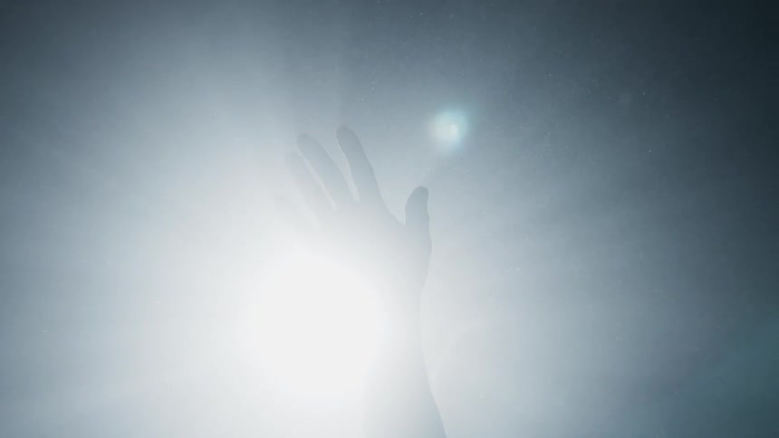 A hand waves in front of a bright light