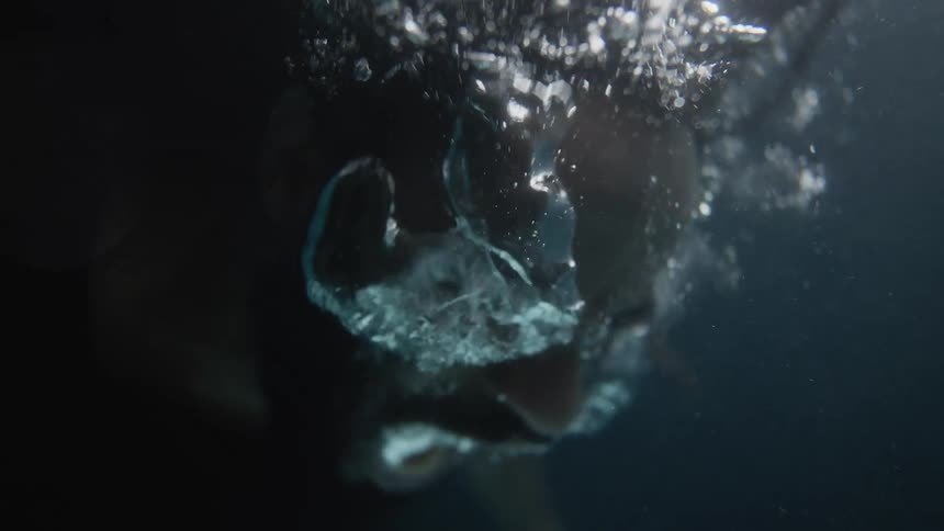 A man shakes his head as he lets out a lot of air underwater
