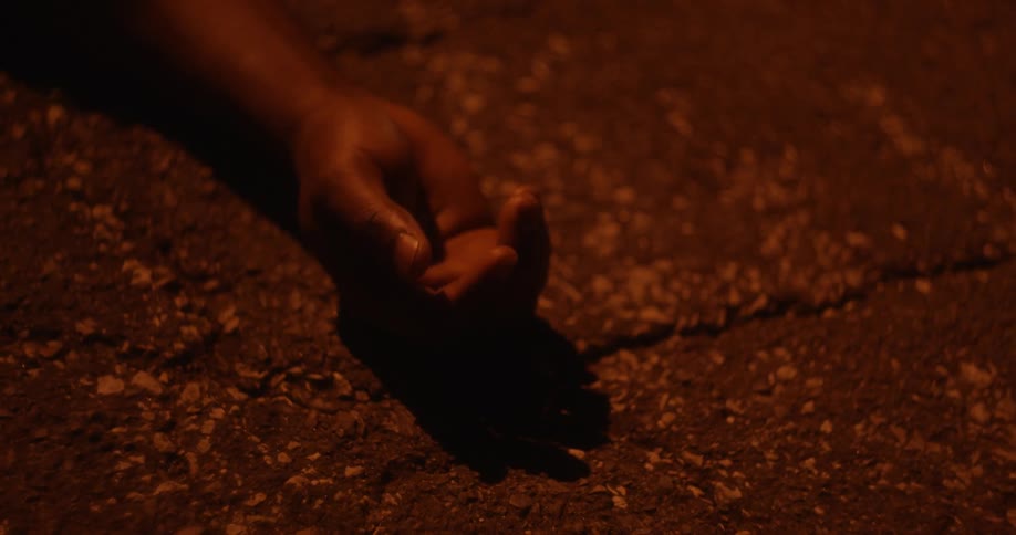 A persons hand laying on the ground outdoors