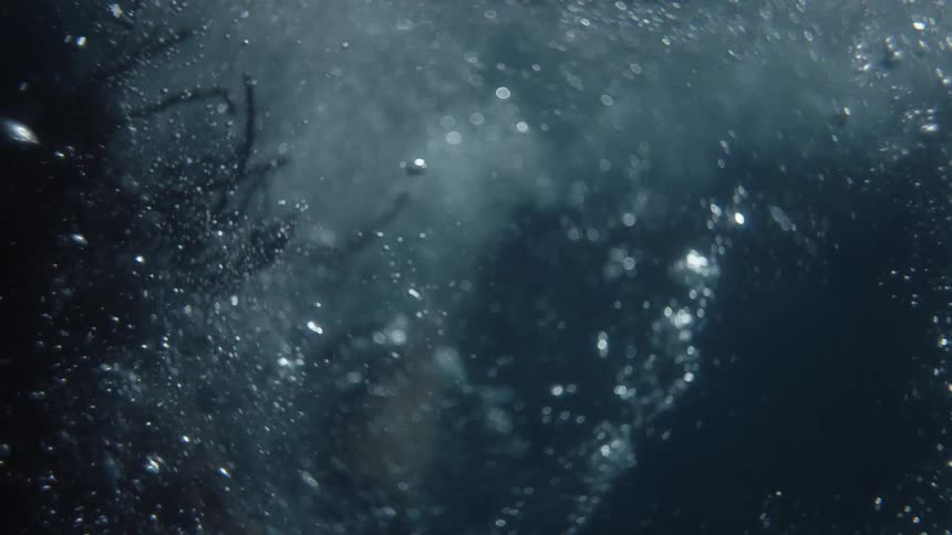 A person diving into water with bubbles