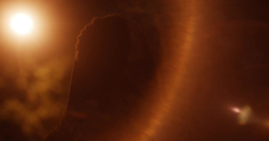 Lights are shining on the face of an angry looking man outside at night