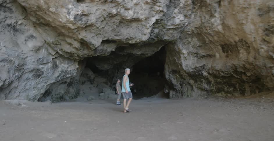 Two people are walking into a cave
