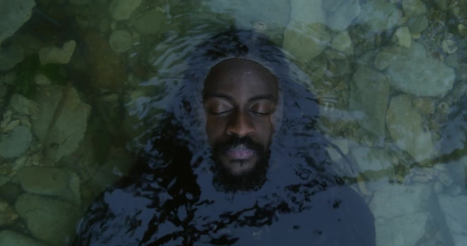 A man laying underwater with rocks