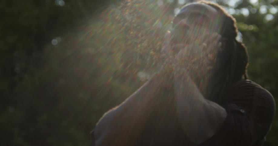 A man rubs his face as he looks up at the sunny sky