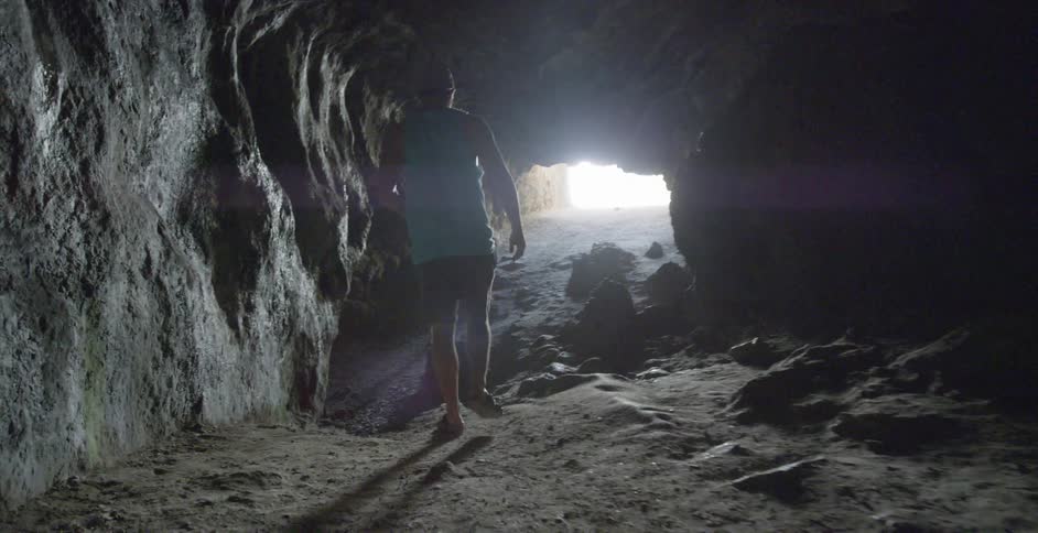A person in a blue shirt walks through a cave