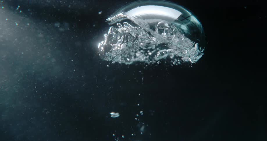 Silver object rise through dark creating bubbles