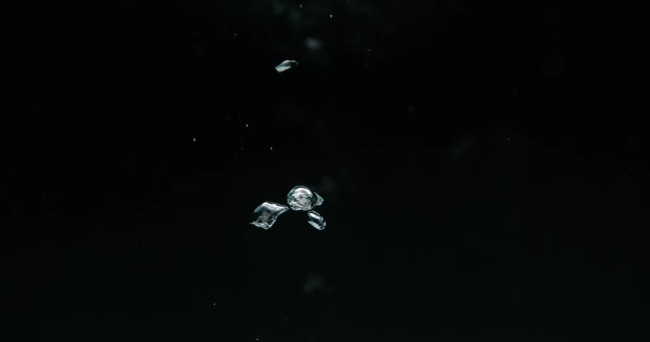 Bubbles float underwater in the dark