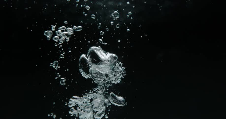 Small water bubbles float upward in a suspended liquid