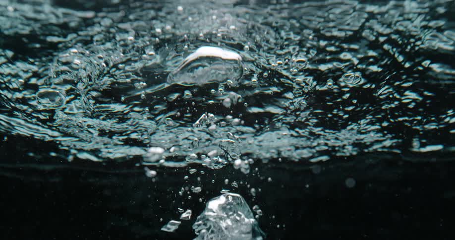 An air bubble rises to the surface of crystal clear water