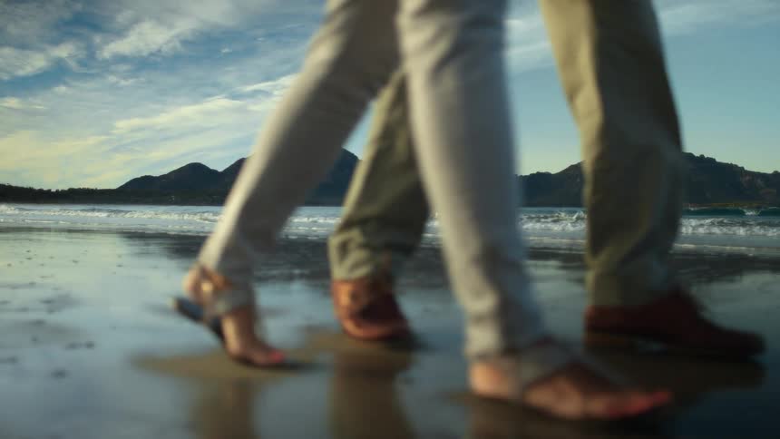 A man and woman walk side by side along the beach
