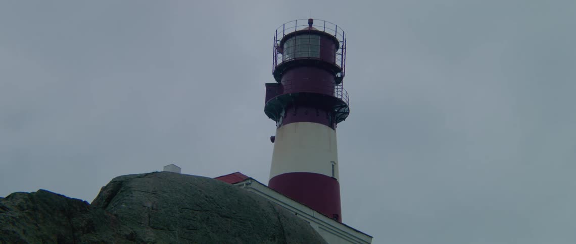 A light house is on the cliff by the shore