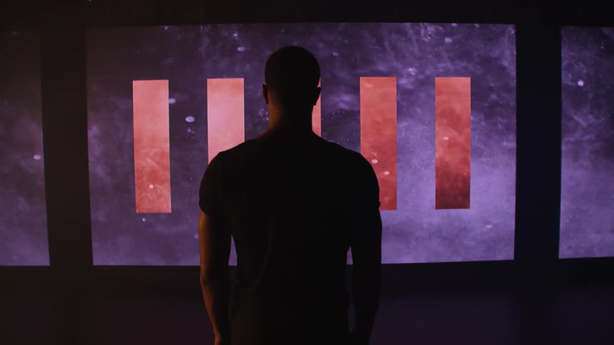 A man looking at screens on a wall