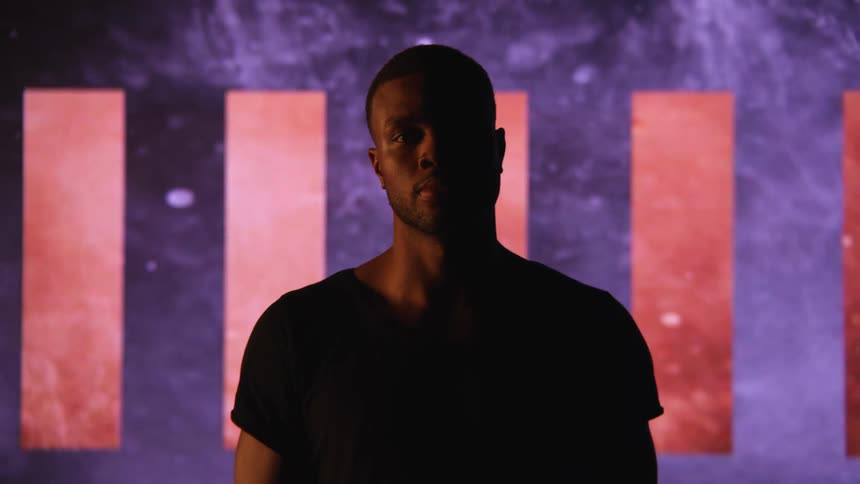 A man turns is head up in front of the huge display behind him