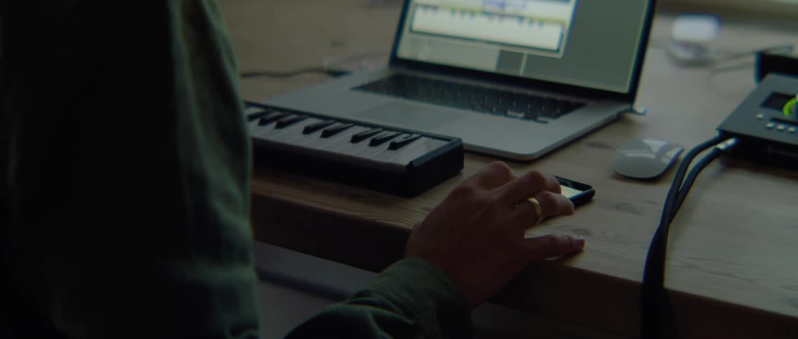 A man is using electronic technology with a keyboard and a laptop computer