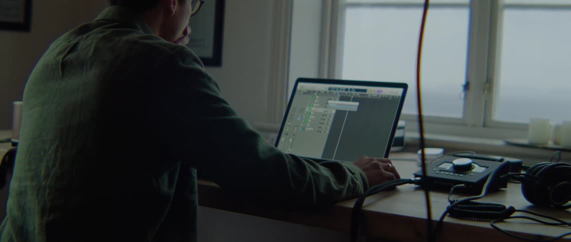 A man is working on a laptop computer and he makes a call on his cell phone