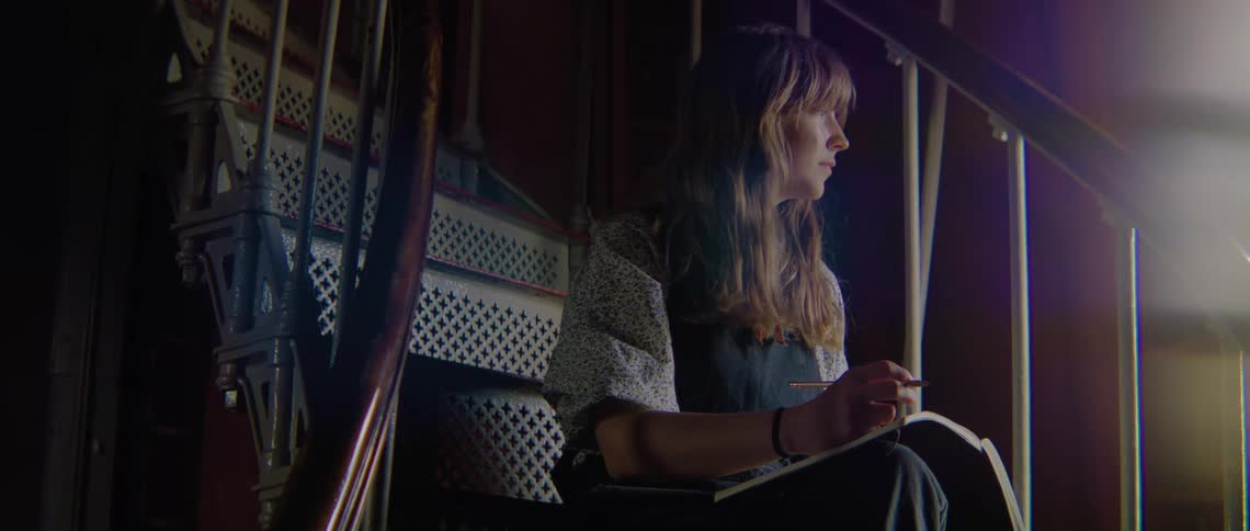A woman is writing in her notebook on the staircase