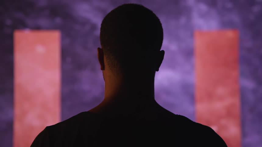 A man stands and watches graphics as they flash on a large screen