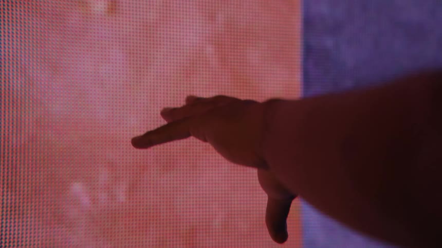 Mans hand reaches to screen with purple and red colors