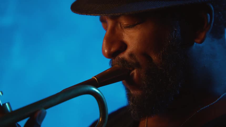 A man wearing a hat is playing a trumpet