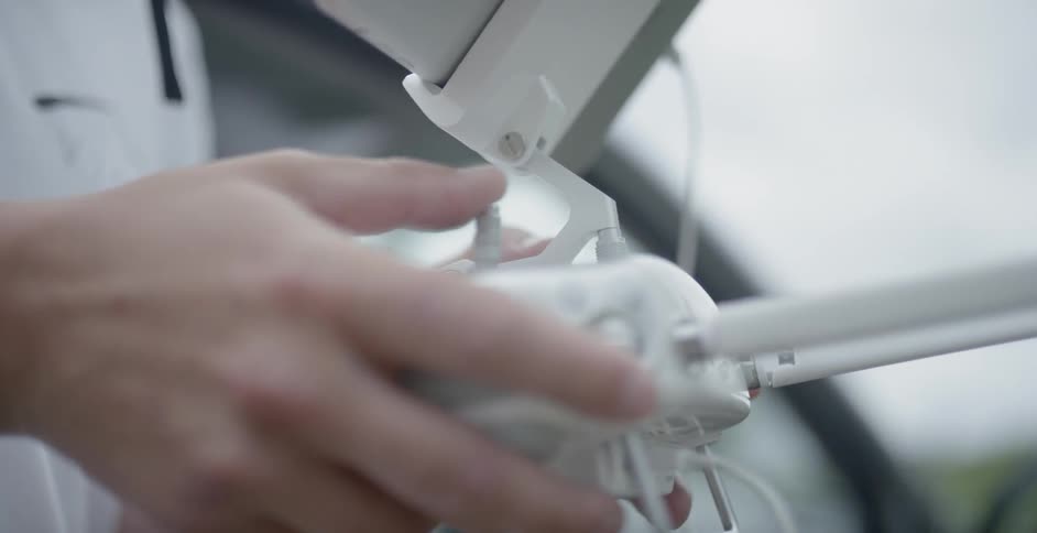 A man stands outside holding a drone remote with screen