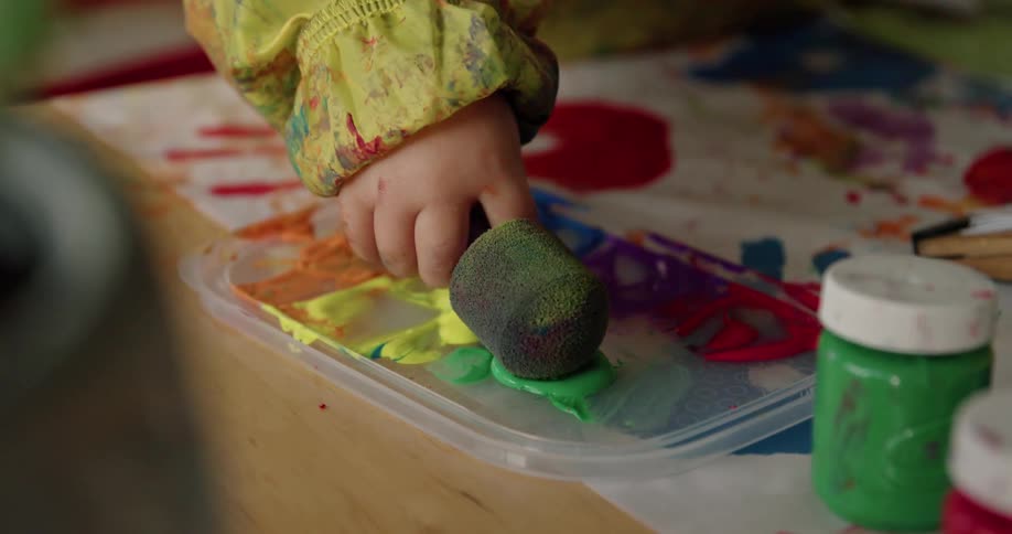 A person dipping a sponge into paint