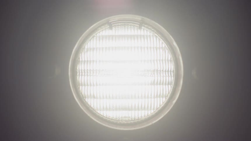An overhead light turns on in a dark room