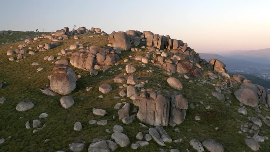Grass is growing on a mountain that is covered with rocks and boulders
