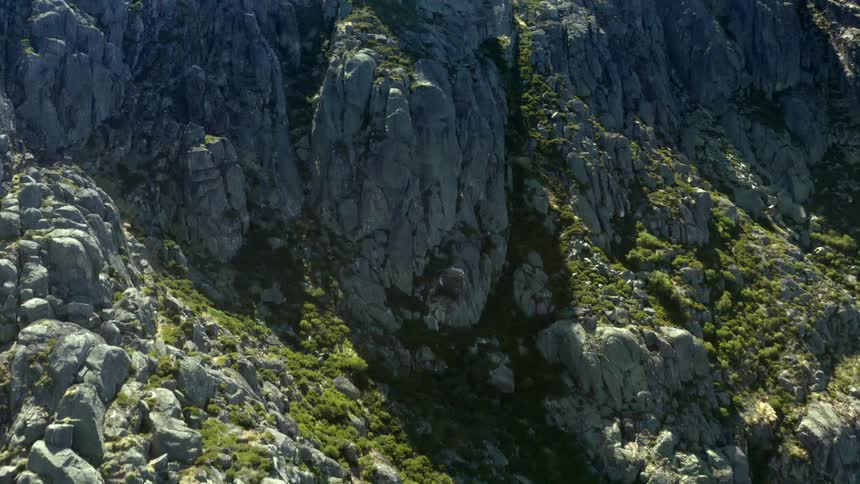 The tall mountain has many edges with green